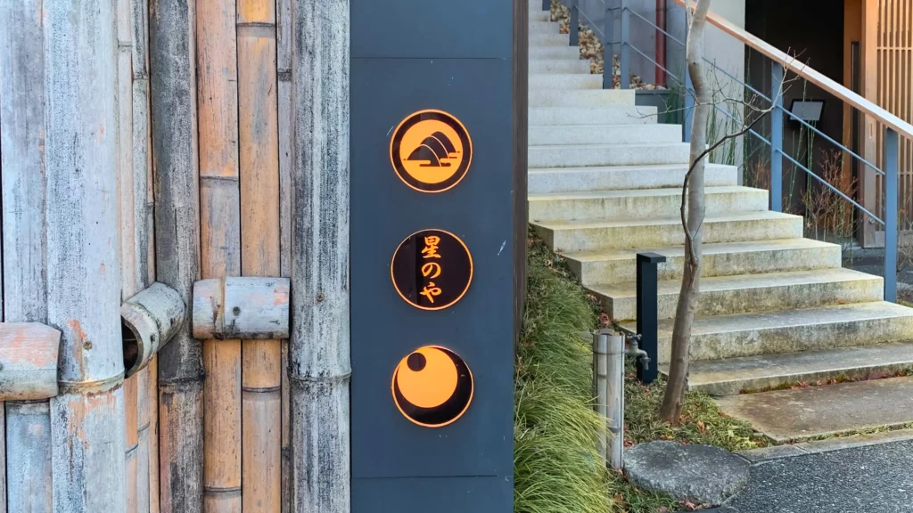 The entrance signage for Hoshinoya Kyoto featuring three circular icons on a bamboo wall.