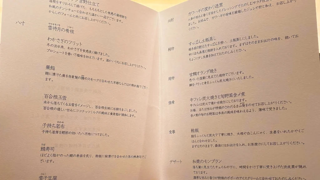 The kaiseki menu card opened showing two pages of calligraphy listing all eleven courses.

