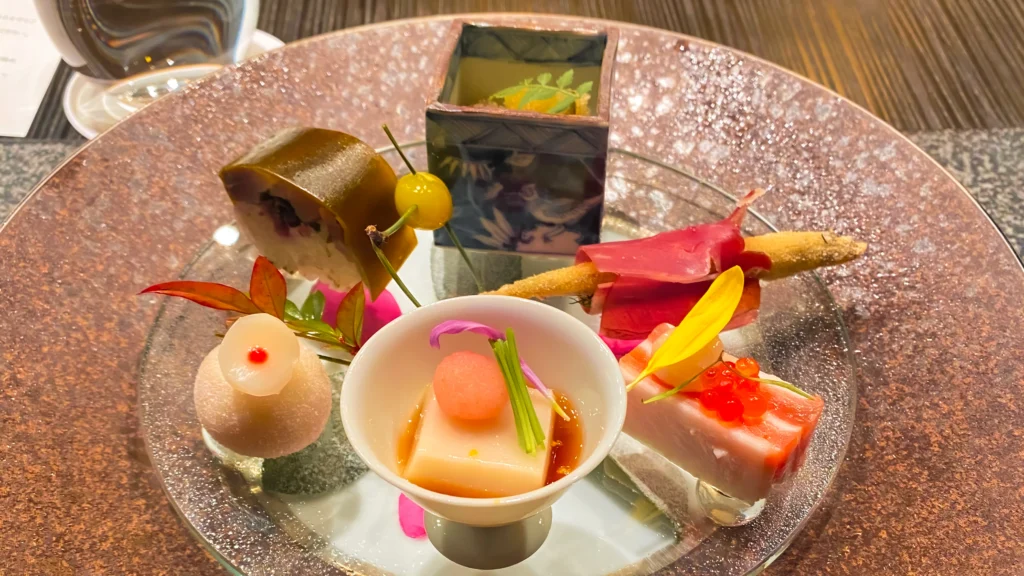 The Hassun appetizer platter featuring a pink glass plate with six delicate bites decorated with autumn leaf accents.