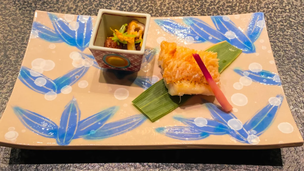 The Yakimono course featuring grilled sea bream served on a fresh bamboo-leaf plate.