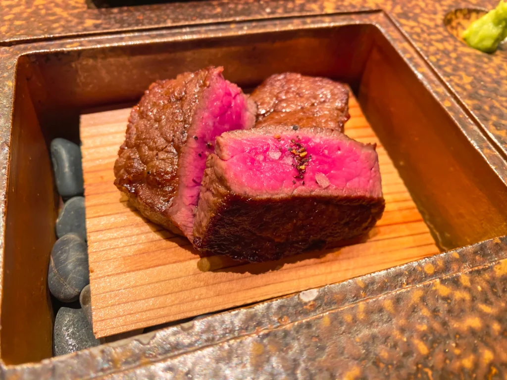 Slices of rare pink Wagyu beef served on hot black river stones with a dab of fresh wasabi.
