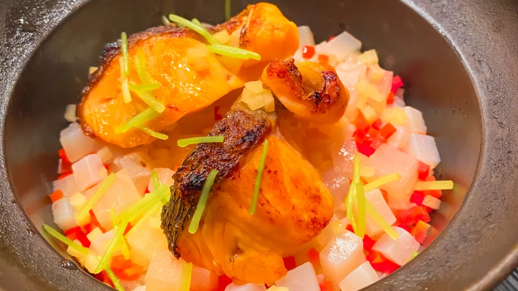 The rice is cooked perfectly in a traditional donabe pot — seared fish on top, ready to be mixed.