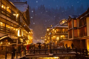 Snow falling on Ginzan Onsen at night, gas lamps illuminating Taisho-era ryokan in Yamagata