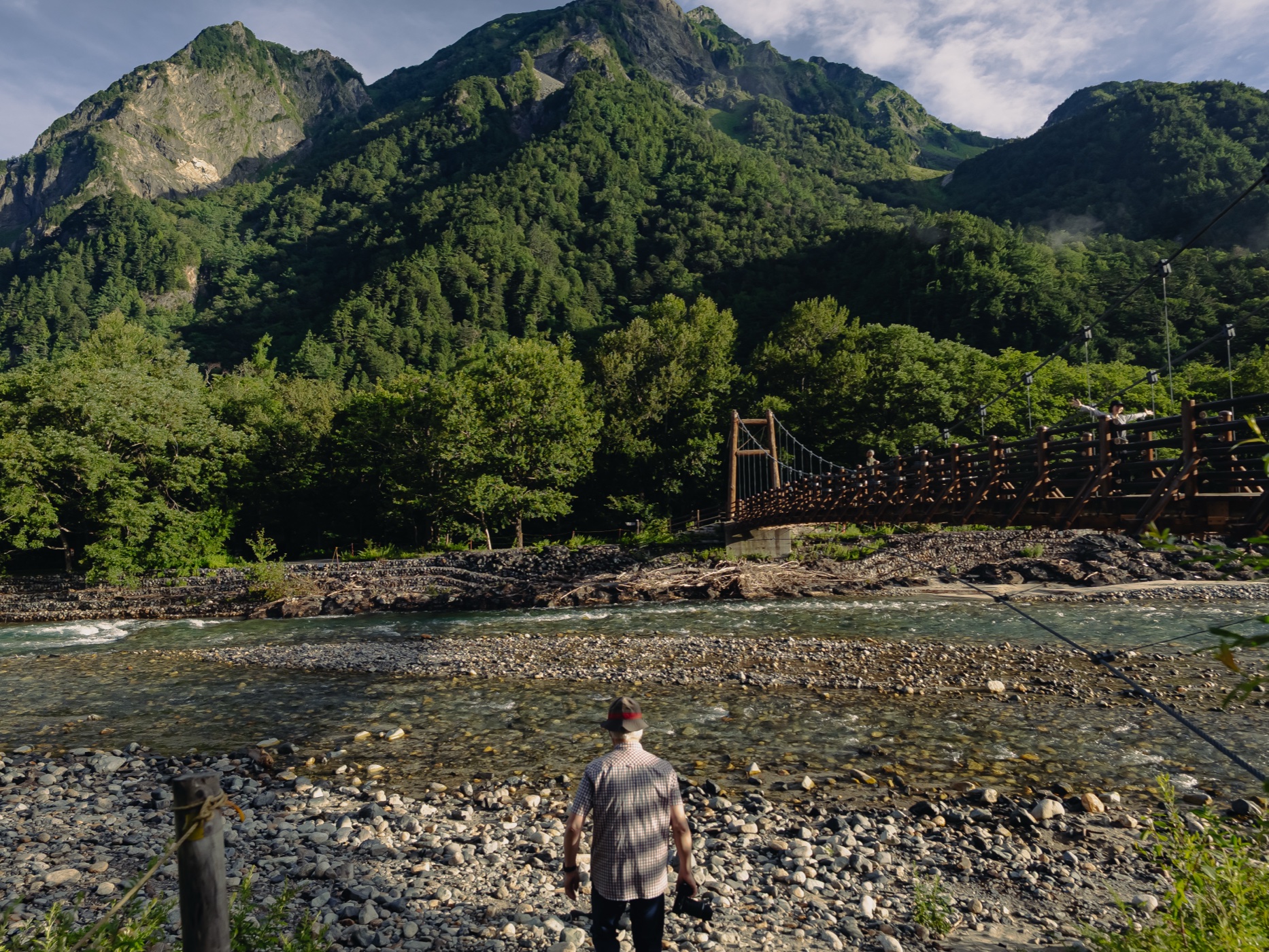 A hiker walking along the forest trail between Kappa Bridge and Myojin with Myojin-dake peak visible through the trees