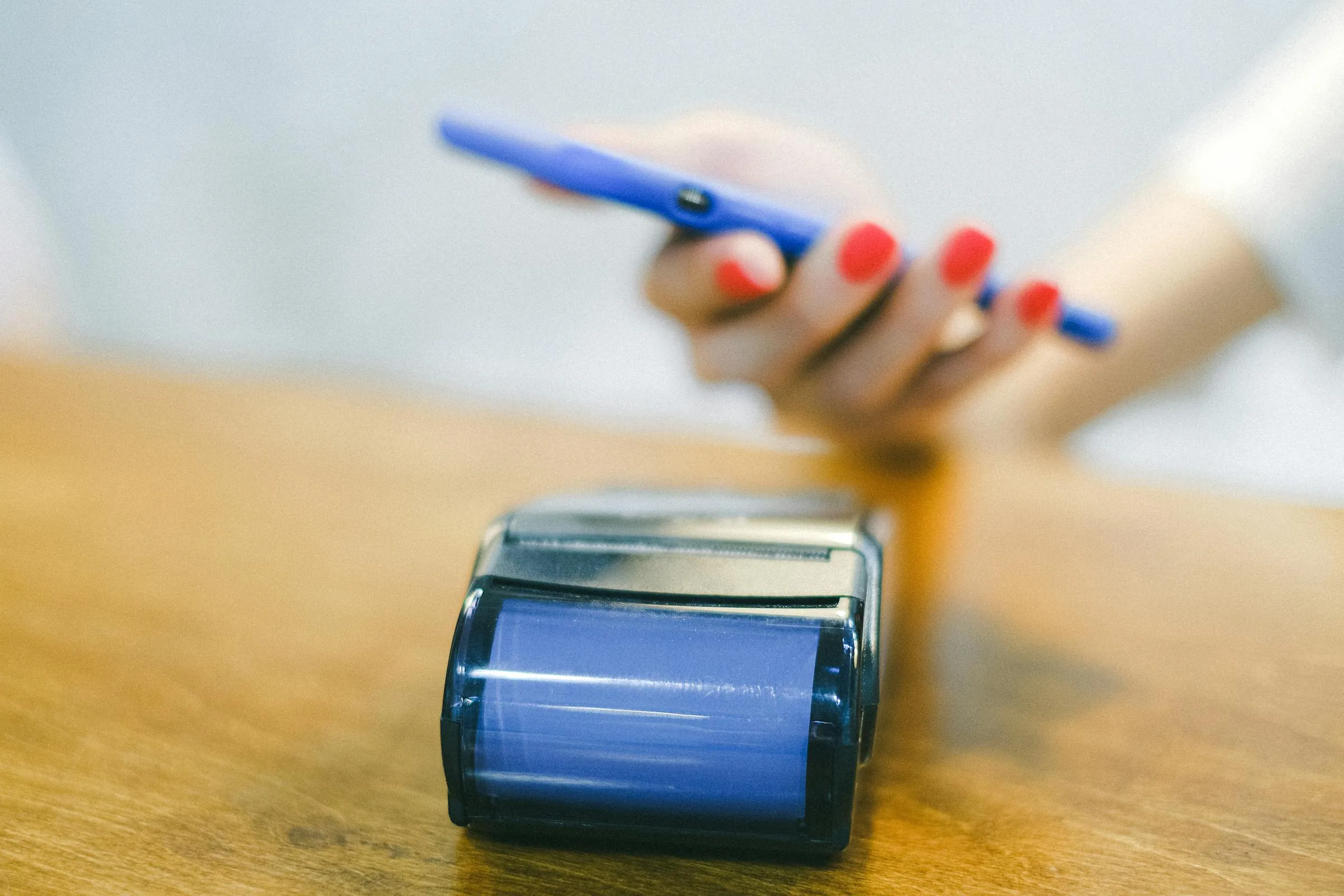 Hand holding a smartphone over a payment card reader terminal on a wooden counter