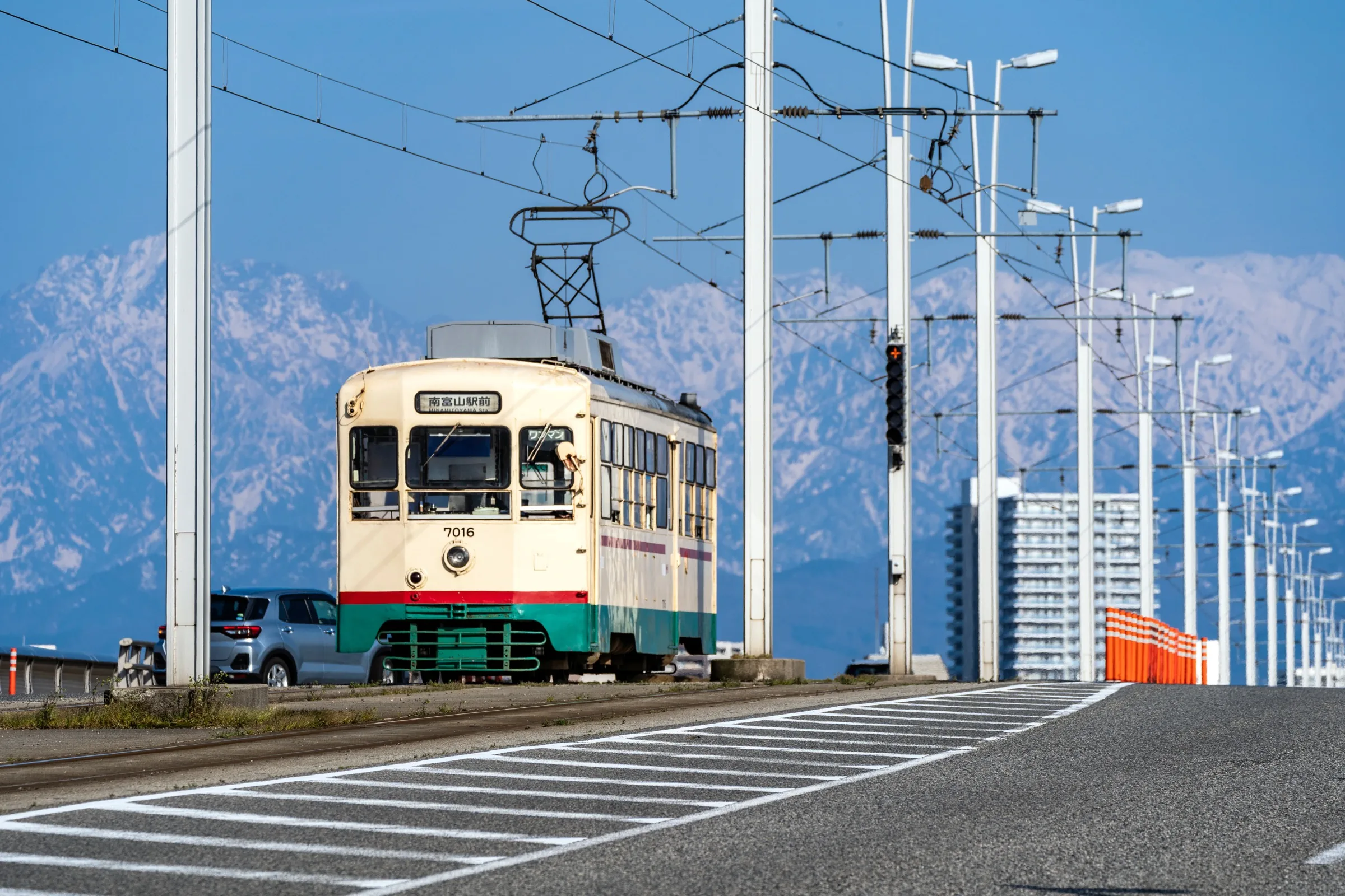 Vintage tram in Toyama city with snow-capped Northern Alps mountains in spring