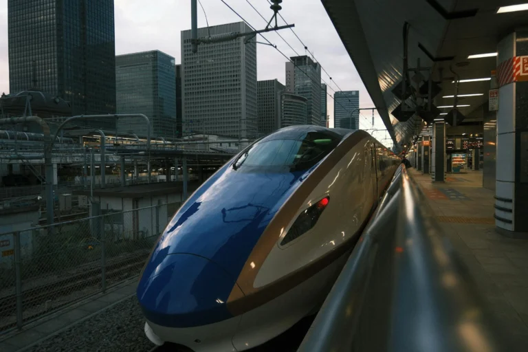 A Hokuriku shinkansen nose at Tokyo Station with the Marunouchi skyline behind, ready to head west