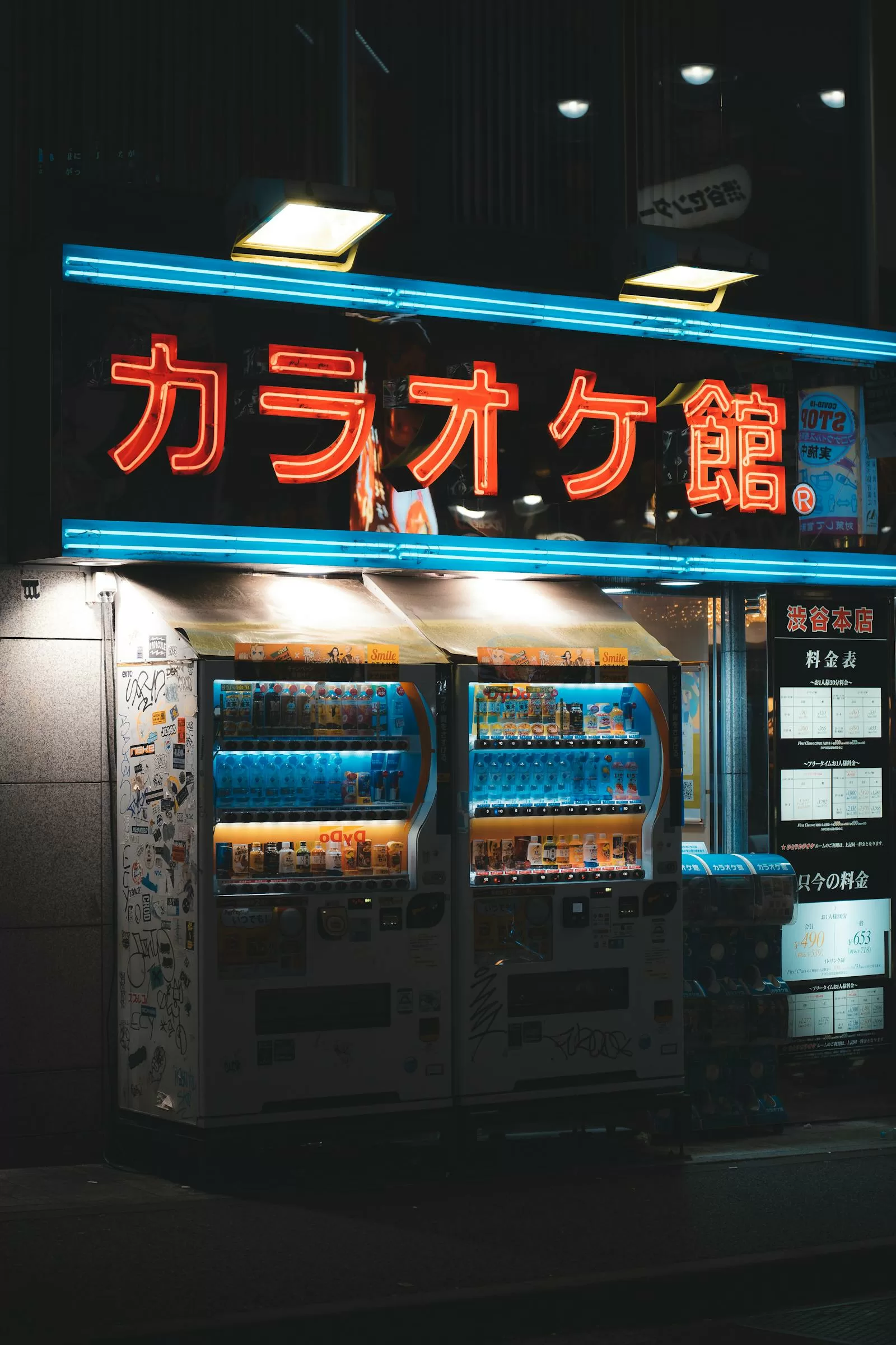 Row of illuminated vending machines on a Japanese city street at night