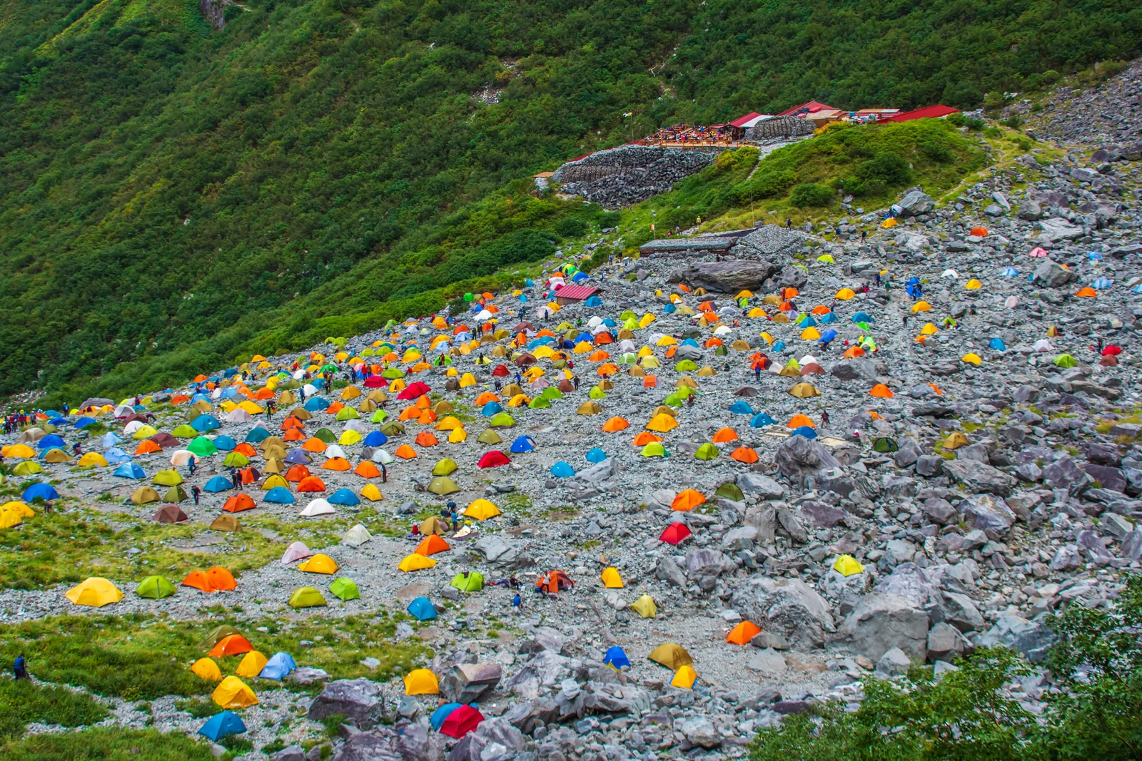 Hundreds of brightly coloured tents pitched on the rocky Karasawa campground floor during the autumn colour weekend, the lodge visible above