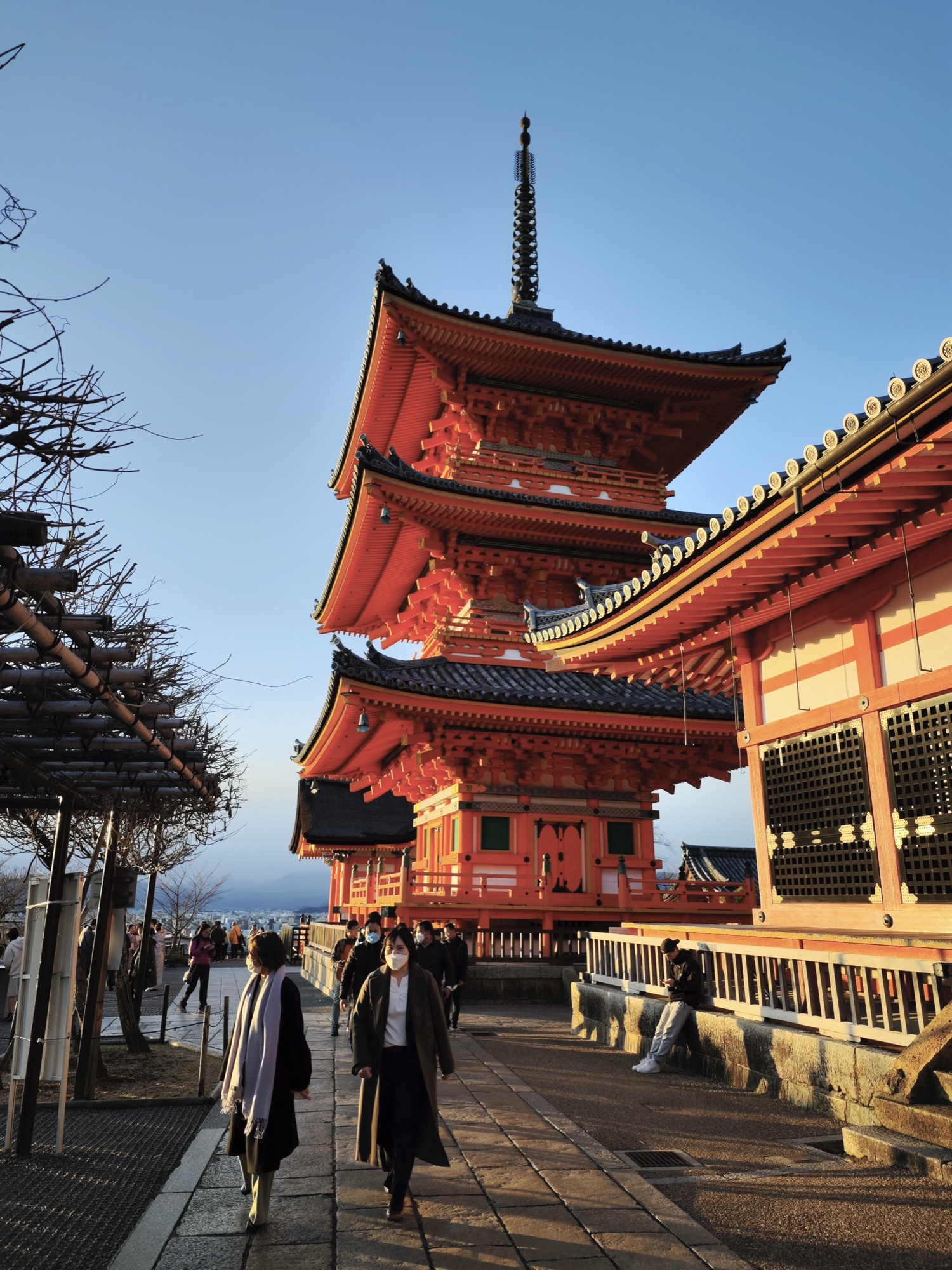 Side profile of Kiyomizudera three-story pagoda showing tiered roof architecture and visitors