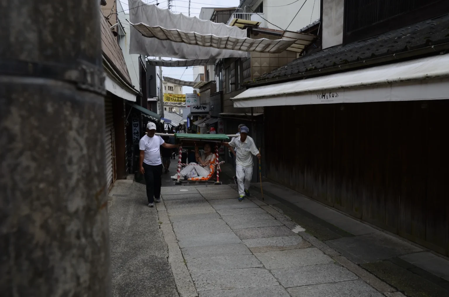 Two bearers carrying a passenger in a kago palanquin along the Kotohira shrine approach