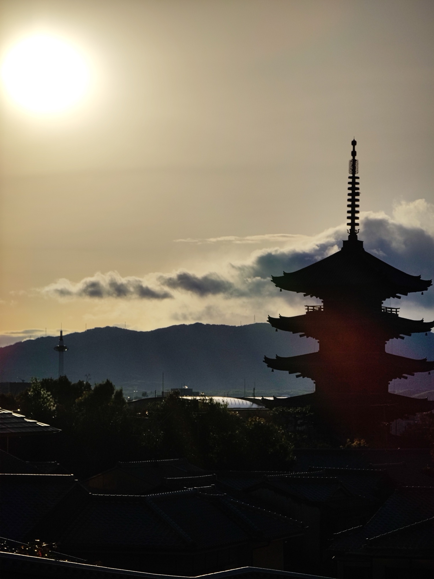 Five-story Yasaka Pagoda Hokanji Temple silhouetted against winter sunset with layered clouds over Kyoto mountains