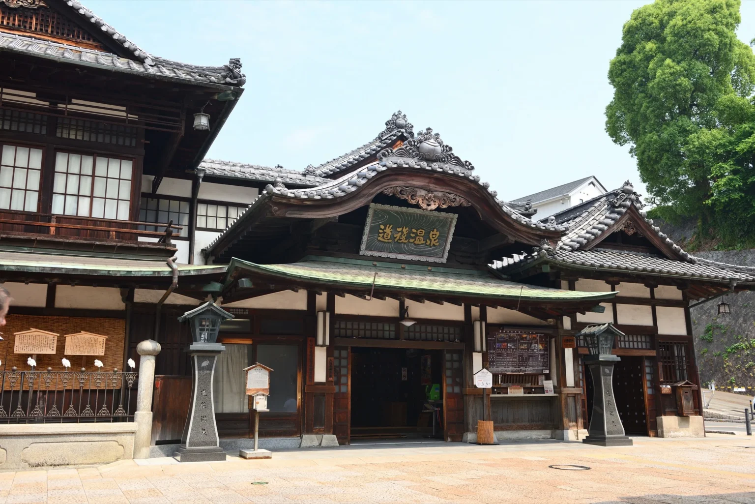The wooden three-storey Dogo Onsen Honkan bathhouse with its curved gable roof in Matsuyama