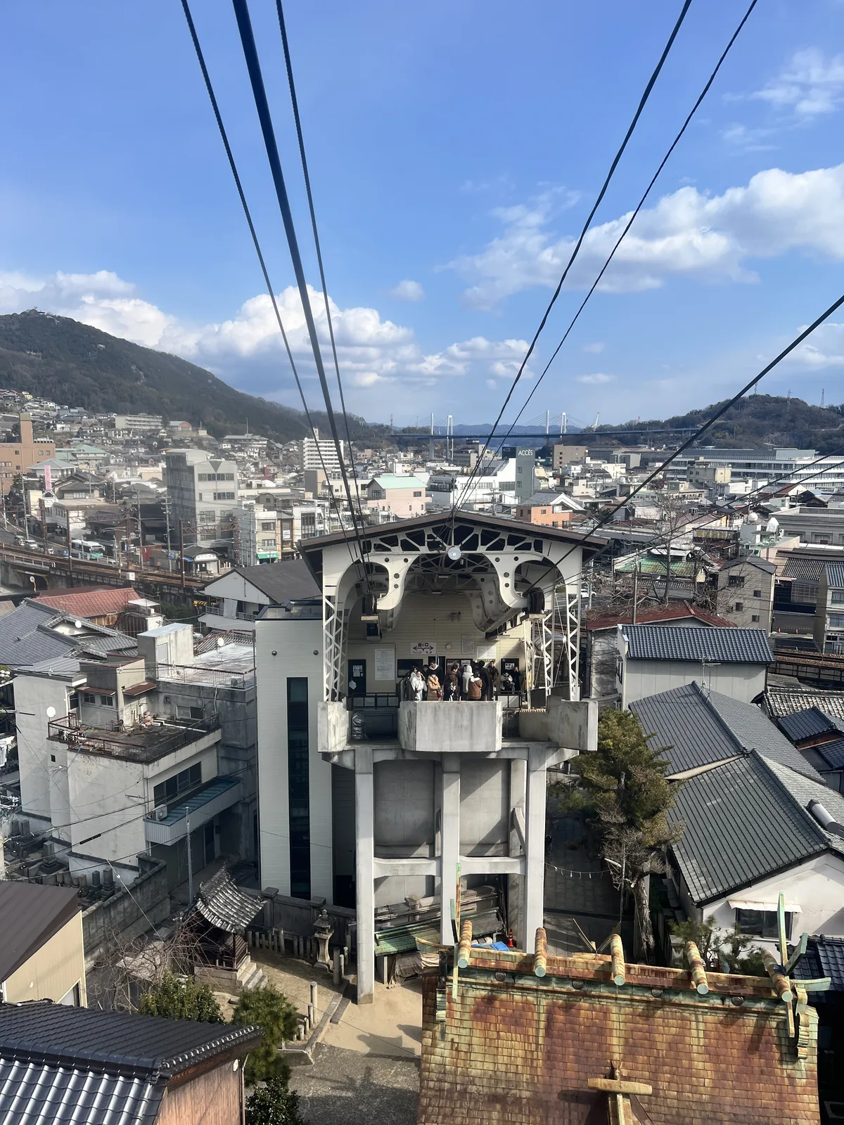The Onomichi Ropeway upper station building seen from the temple grounds, with cables trailing down toward the town below