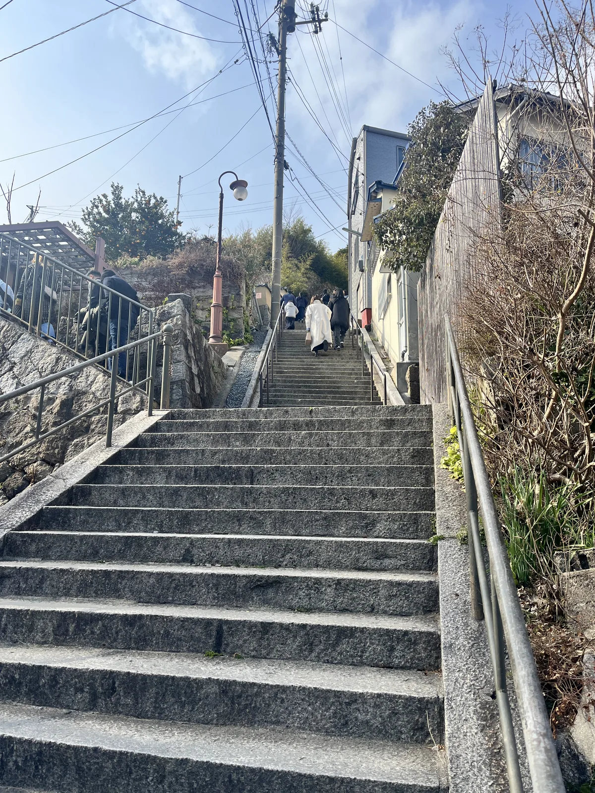 Stone steps in Onomichi with two visitors in white walking up between traditional houses