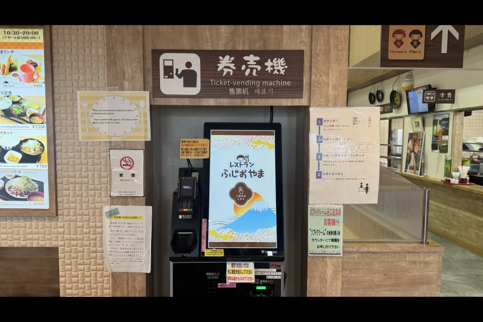 Self-service ticket vending machine at Restaurant Fujioyama with English instructions posted beside it