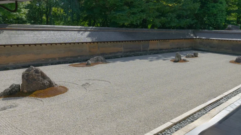 Ryoanji rock garden full view with raked gravel rocks and earthen wall in Kyoto