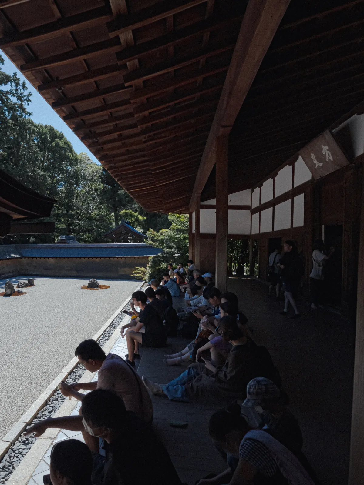 Vertical view of Hojo veranda with visitors seated looking at the garden