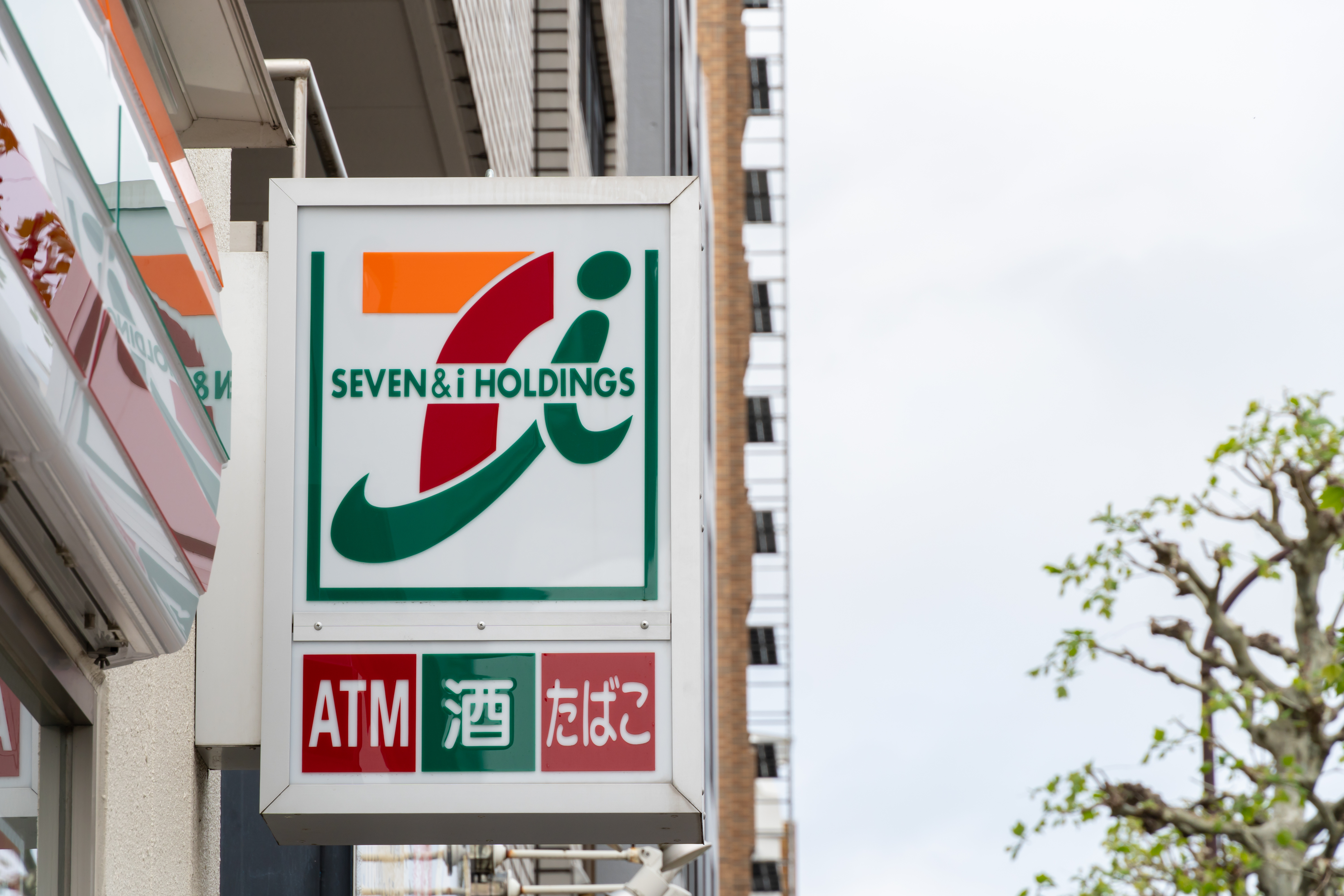 7-Eleven Seven and i Holdings sign with a red ATM subsign on a Tokyo street