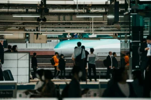 Crowd of travelers waiting on a Tokyo Station platform as a green Hayabusa shinkansen stops beside them