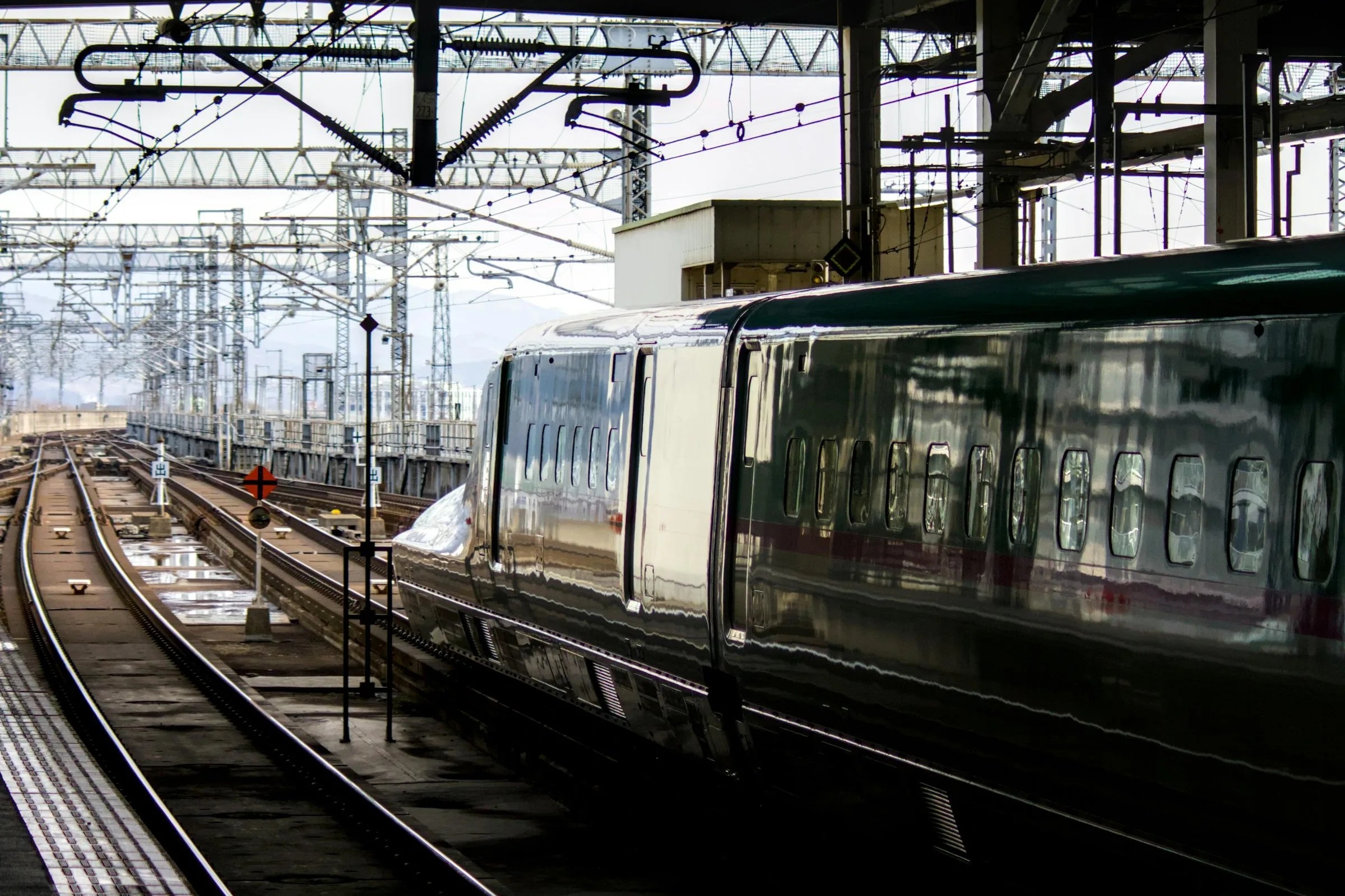Side view of a shinkansen bullet train leaving a Japanese station platform