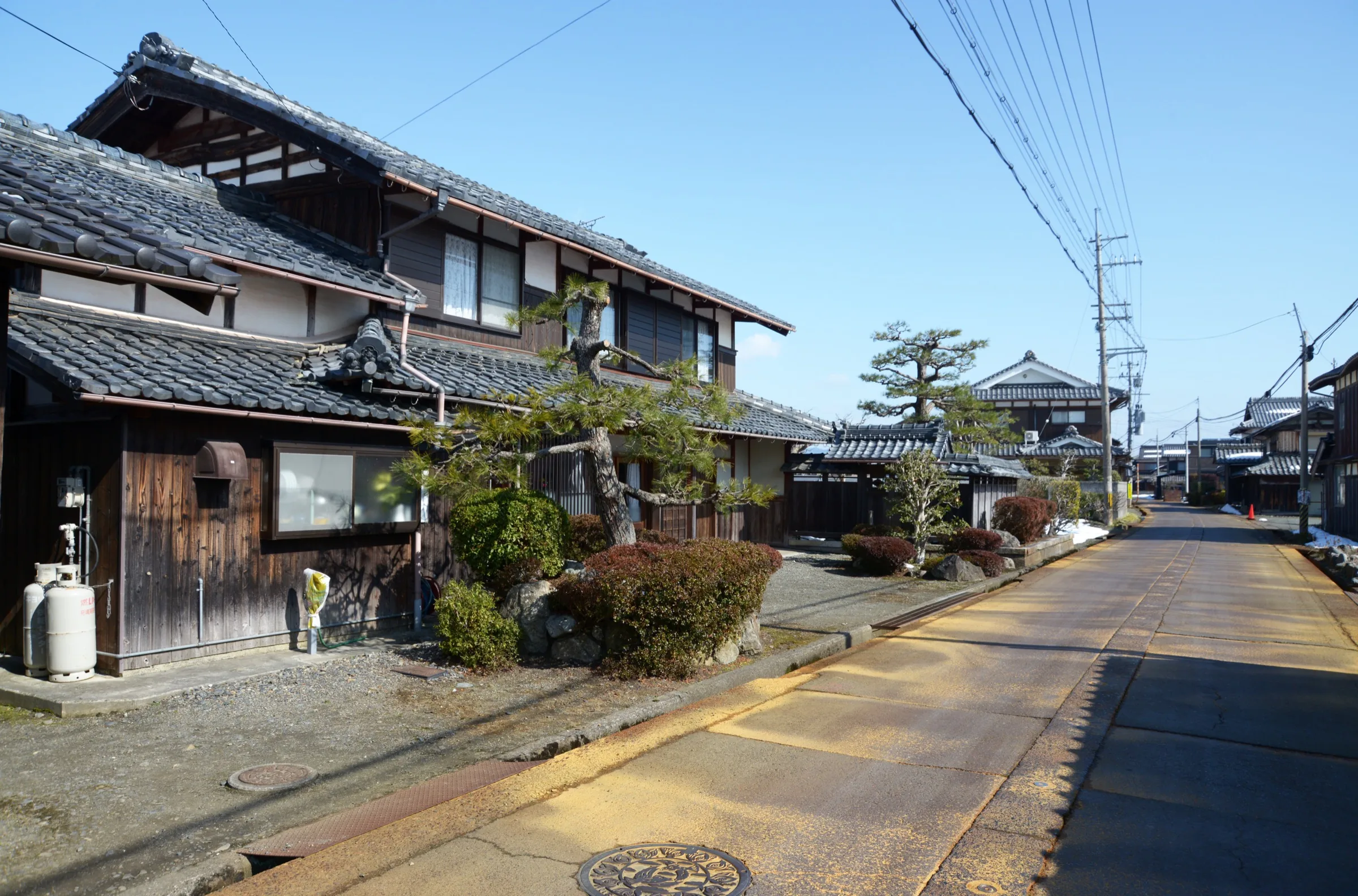Quiet Takashima street with two-story dark-wood traditional Japanese houses on a clear winter day