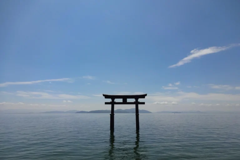 Vermillion Shirahige Shrine torii standing in Lake Biwa with calm water and distant mountains