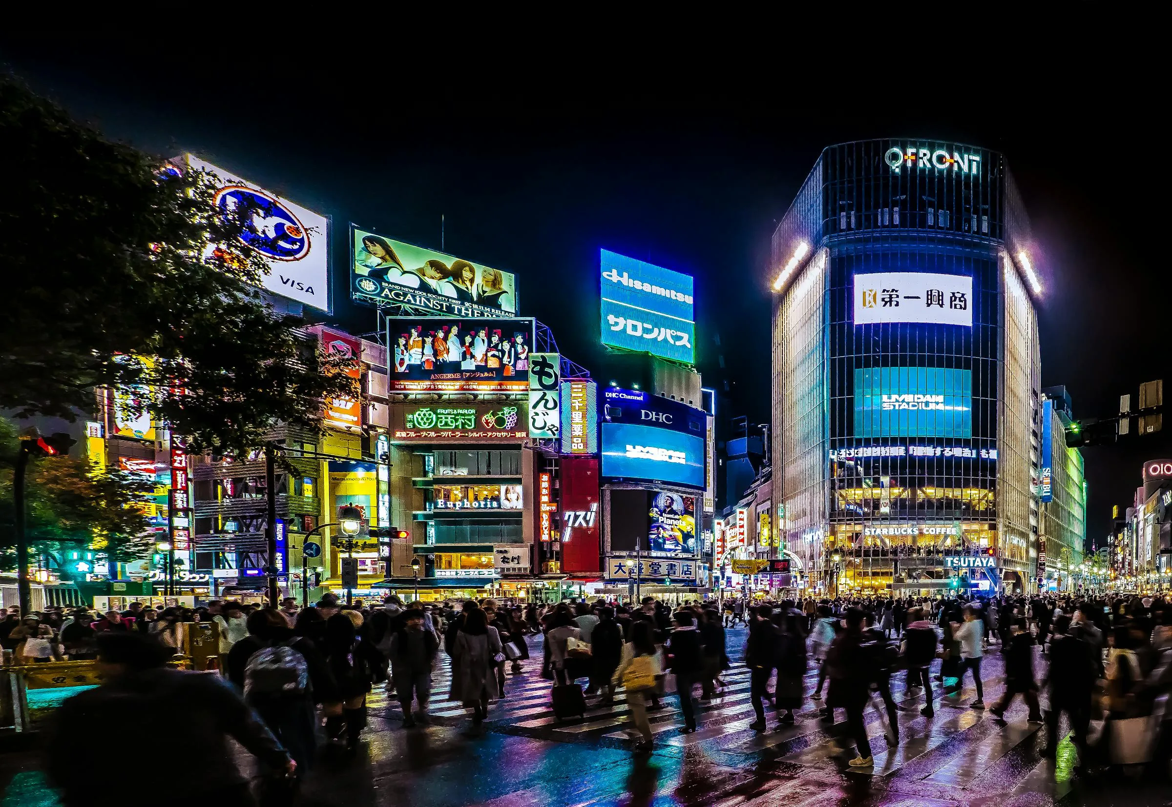 Crowds crossing Shibuya Scramble at night under colourful neon billboards in Tokyo