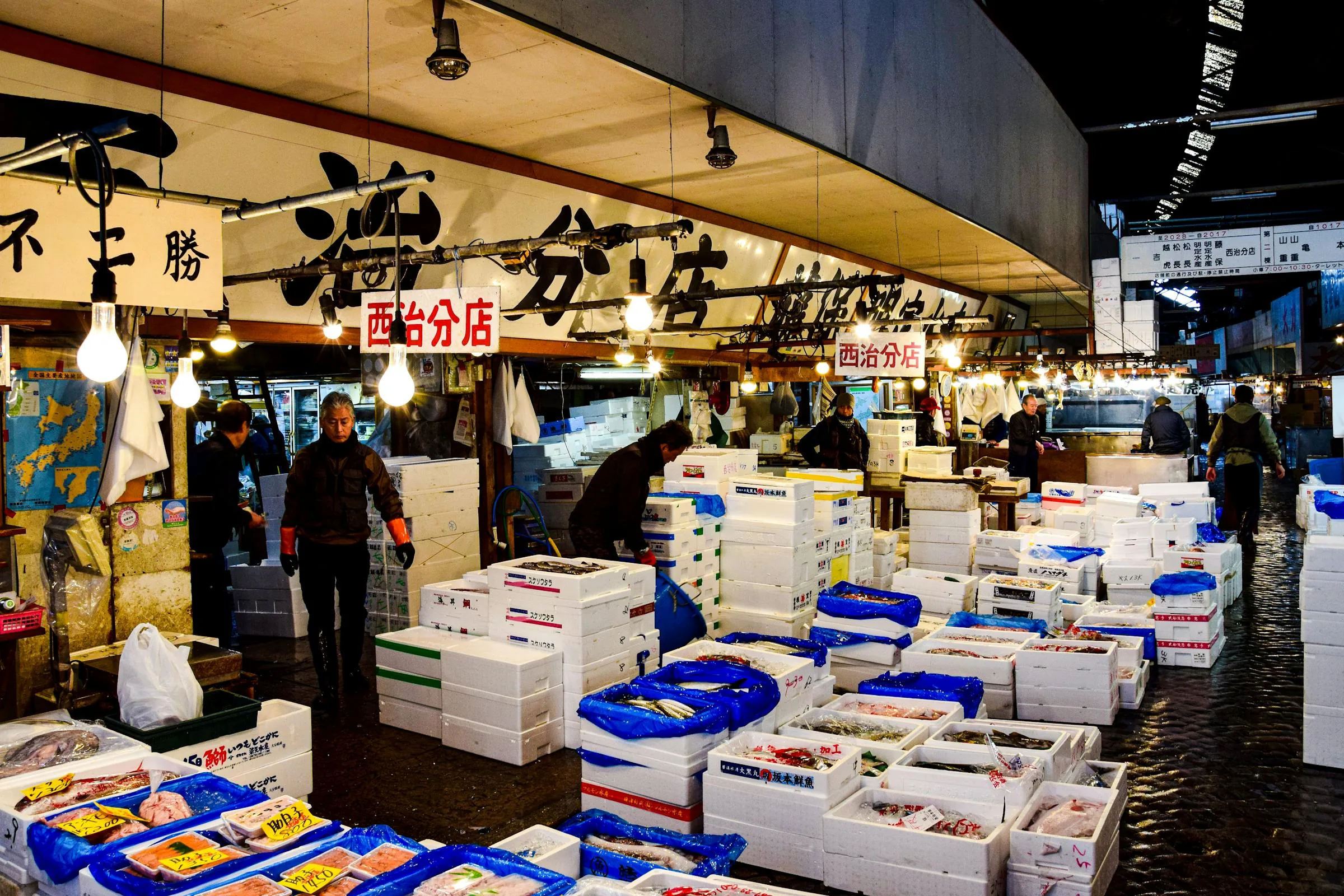 Vendor at Tsukiji outer market in Tokyo with stacked seafood crates in the foreground