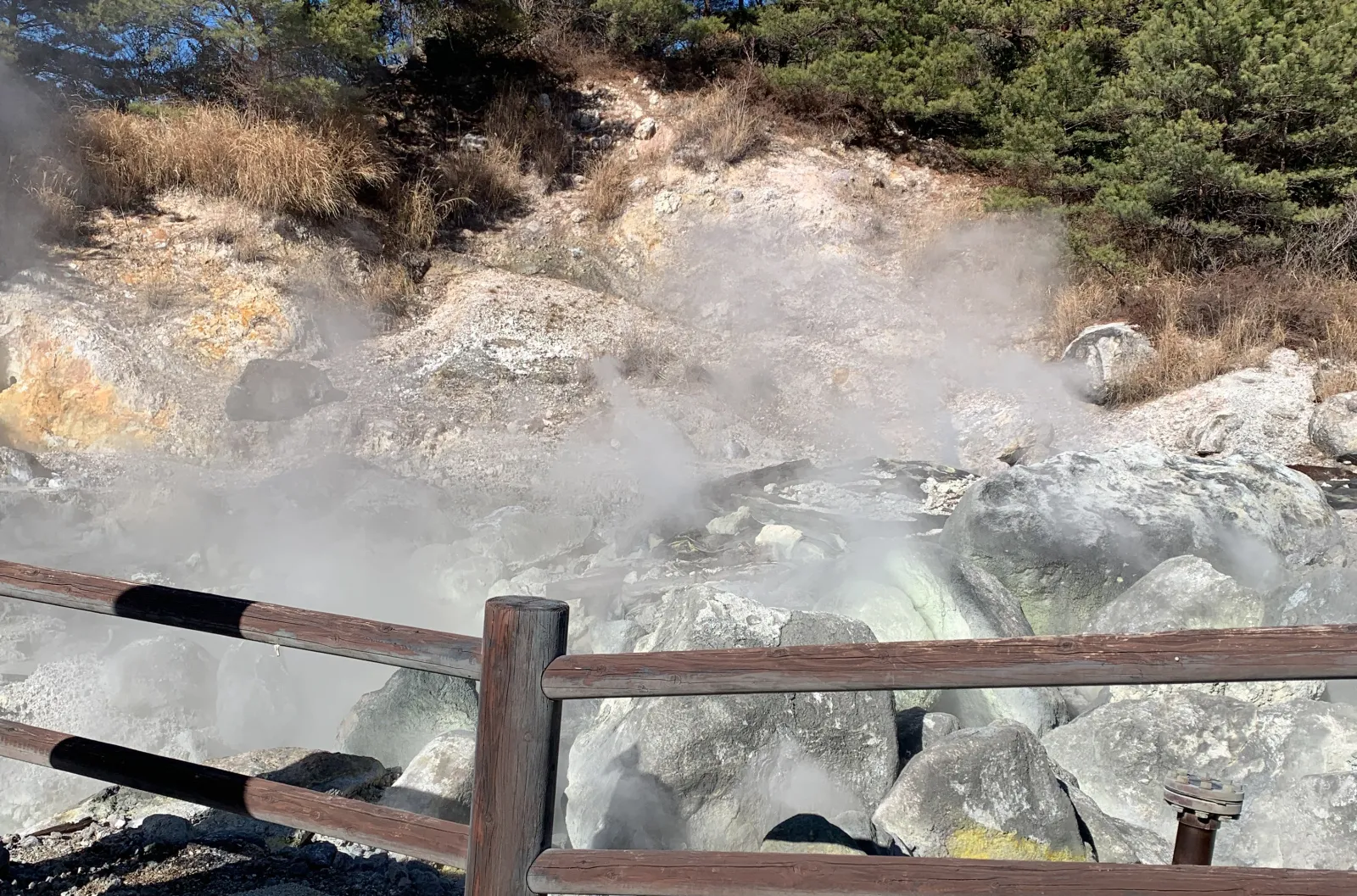 Steam rising from volcanic rocks at Unzen Jigoku with wooden railing