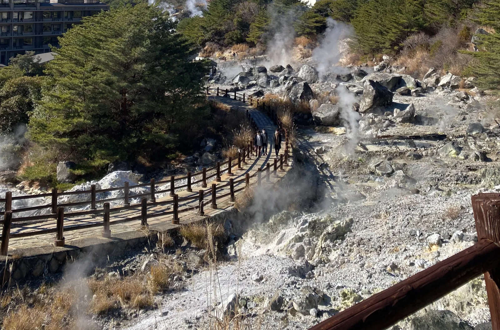 Wooden walkway through Unzen Jigoku with steam vents and visitors