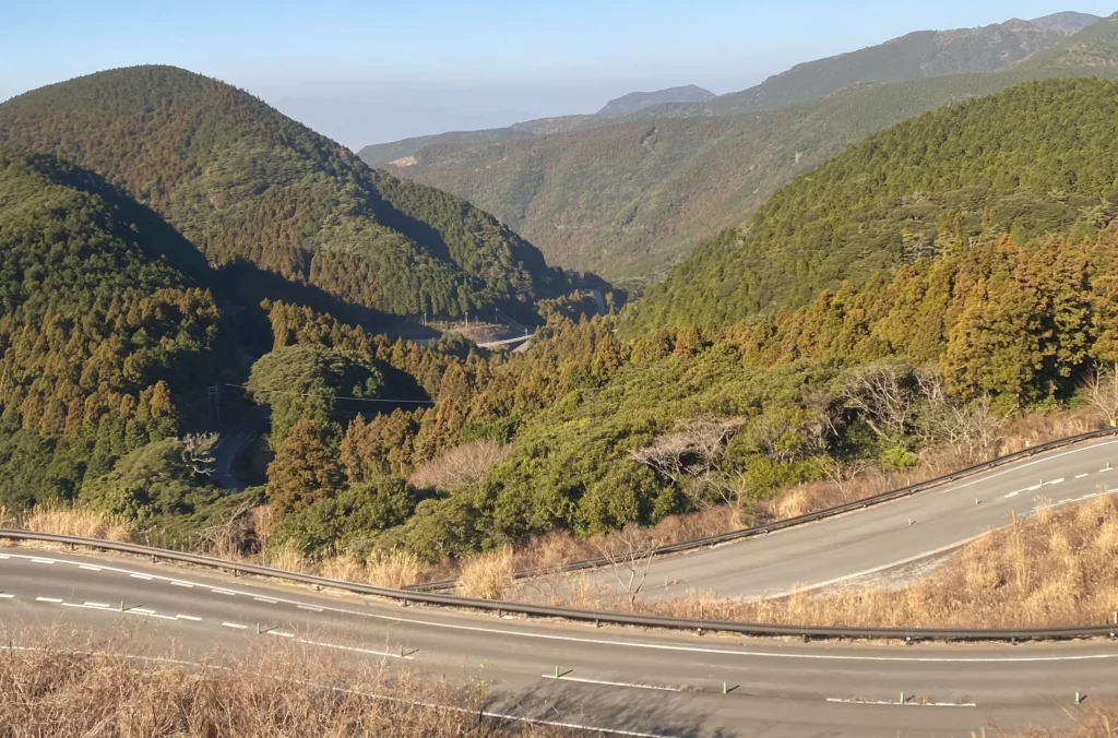 shimabara-peninsula-mountain-road-valley.jpg — Mountain road curving through Shimabara Peninsula volcanic valley