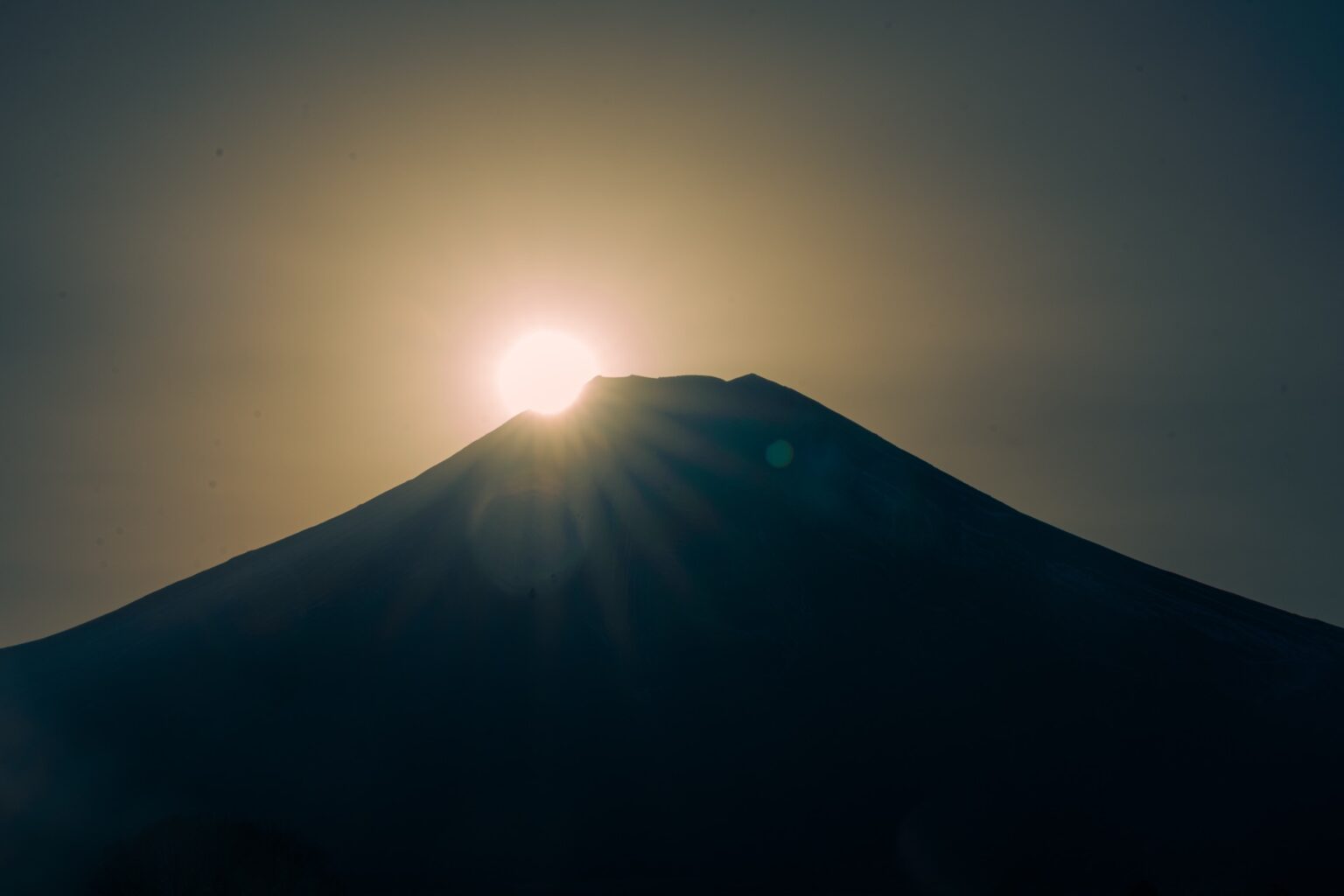 The sun touching the summit of Mt. Fuji at the Diamond Fuji moment with rays radiating from the peak