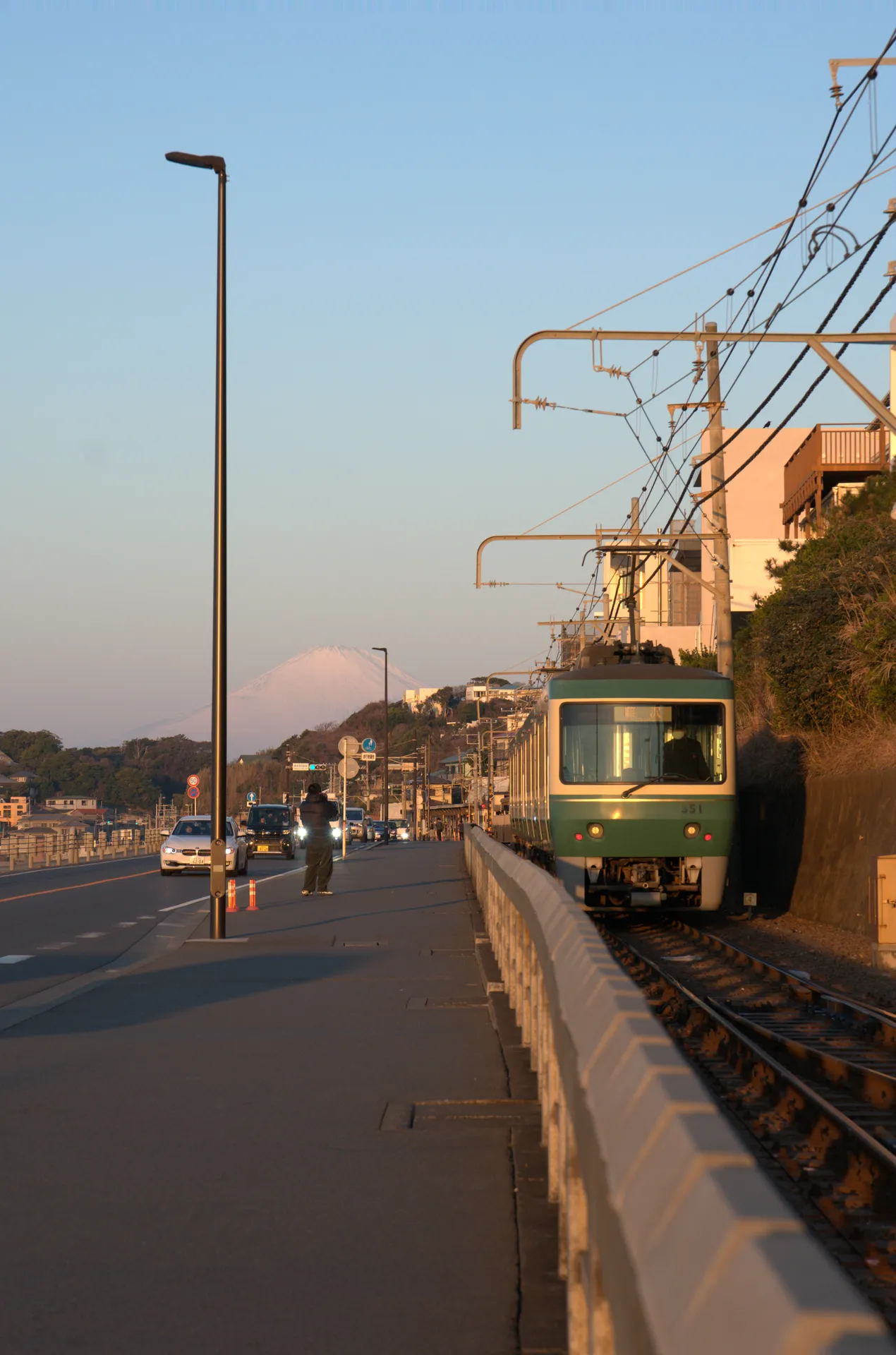 Enoshima Electric Railway green train passing through Shonan with Mt Fuji silhouette visible in the morning haze