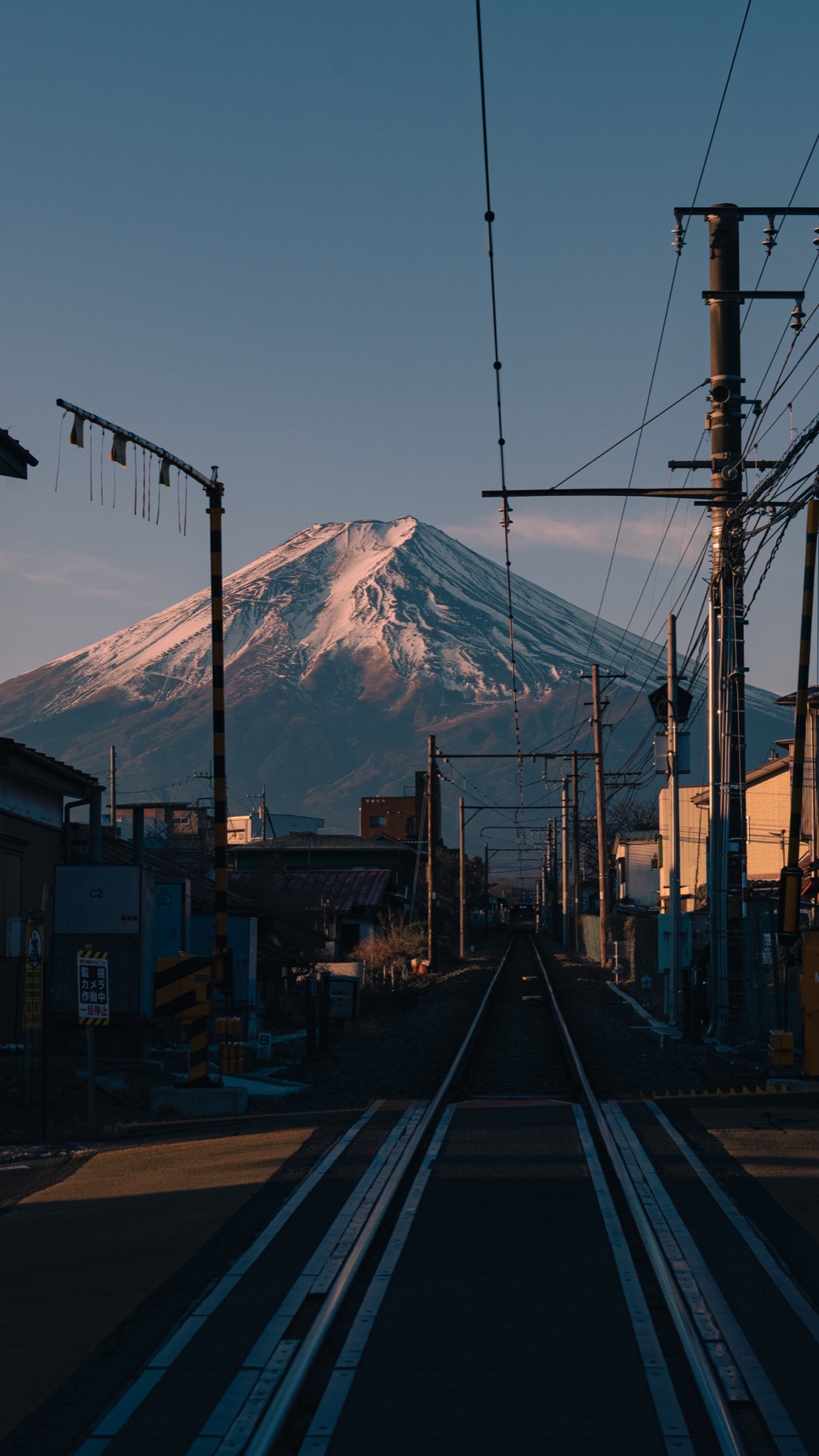 Fujikyu Railway tracks running straight toward Mt Fuji with the summit still glowing pink from sunrise alpenglow February 6 2026 between Shimoyoshida and Mt Fuji Station