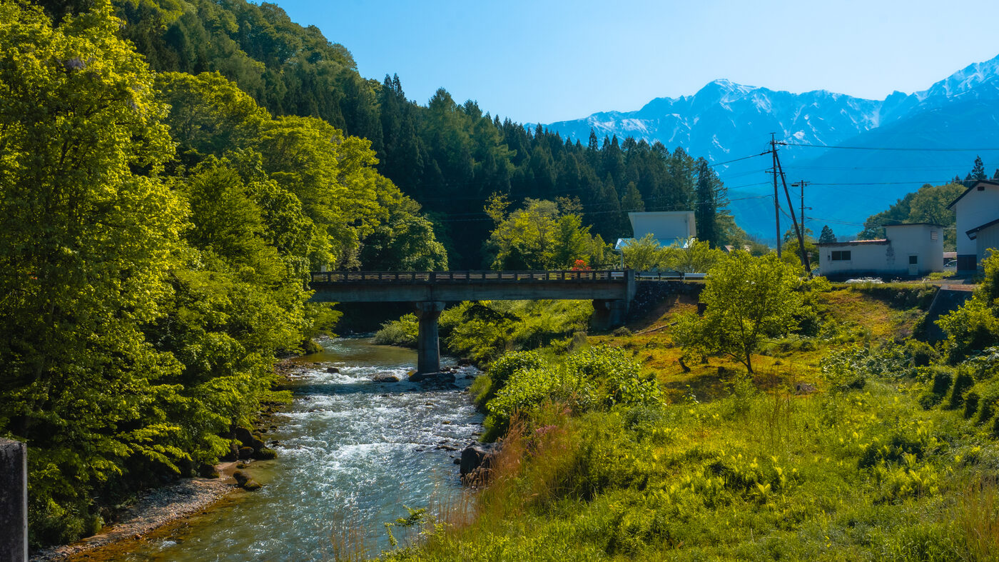 Hakuba in spring: green river bridge with snow-capped Northern Alps in background