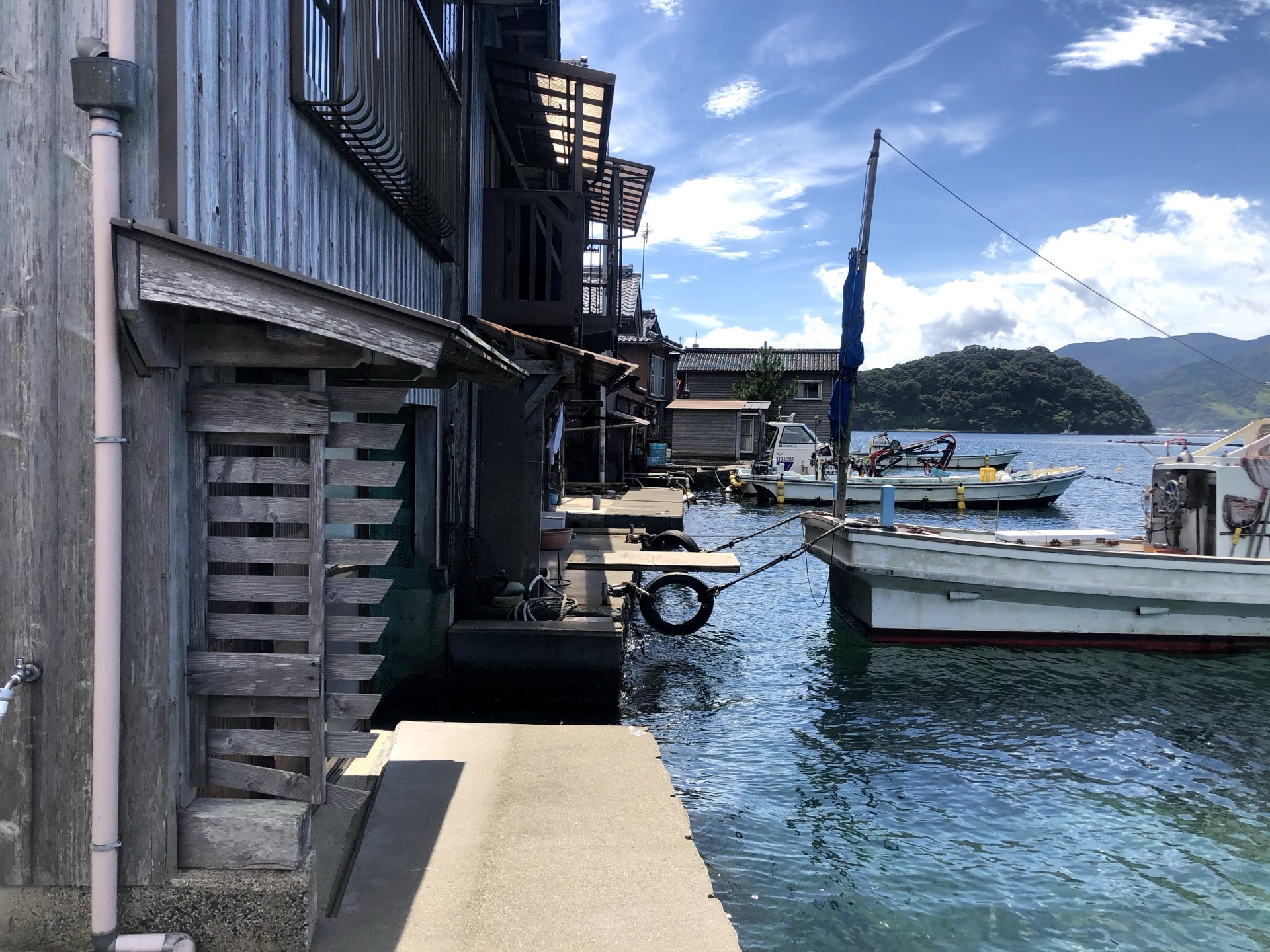 Walking past funaya from the dockside path with fishing boats moored alongside