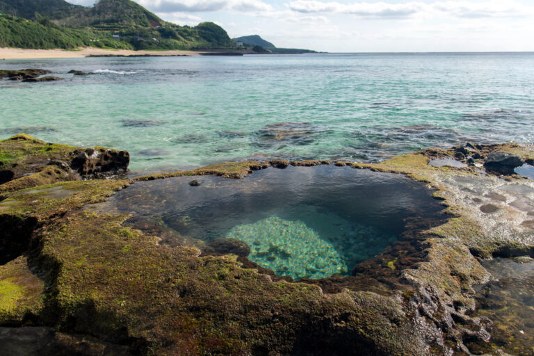 Crystal-clear coastal tide pool surrounded by mossy rock on a Kagoshima island