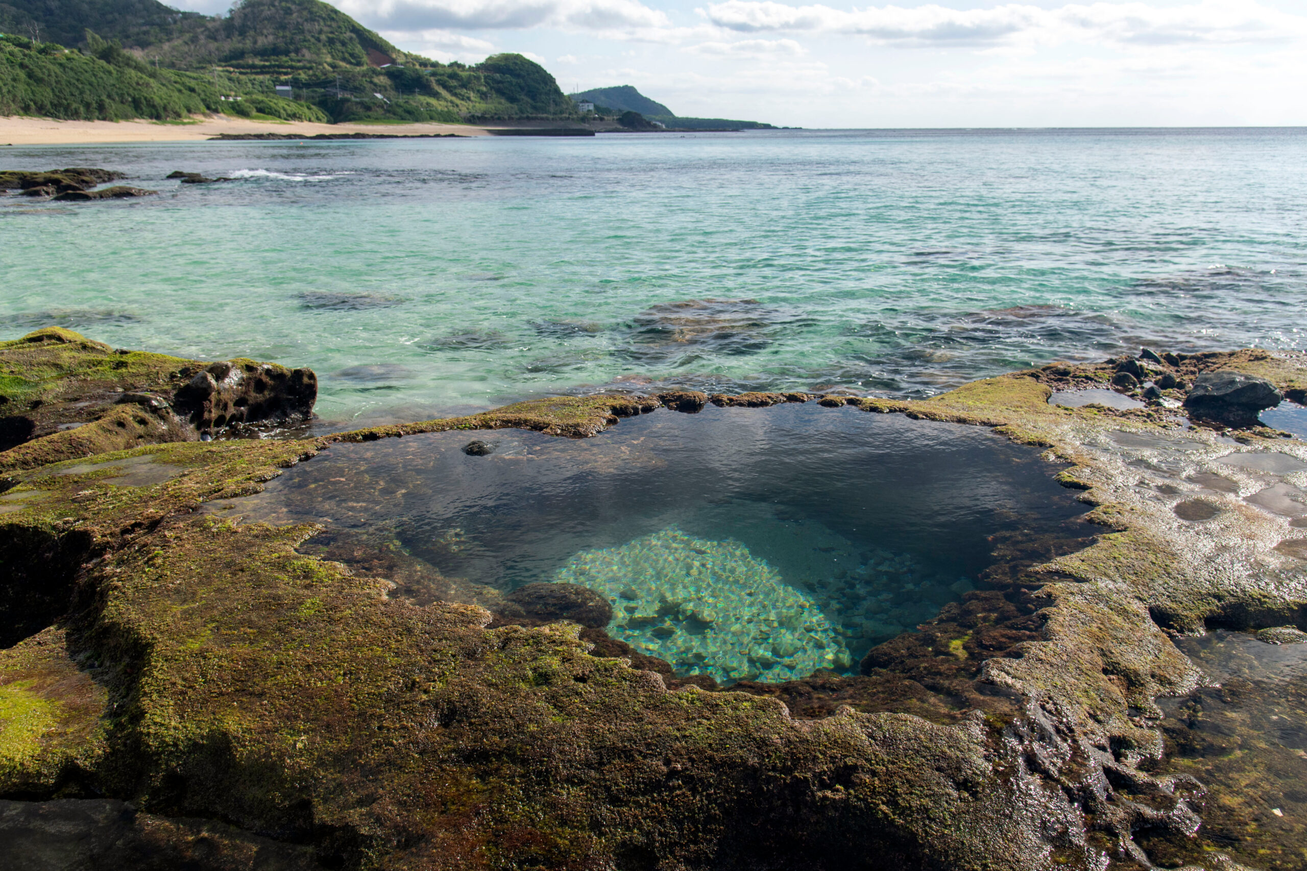 Crystal-clear coastal tide pool surrounded by mossy rock on a Kagoshima island
