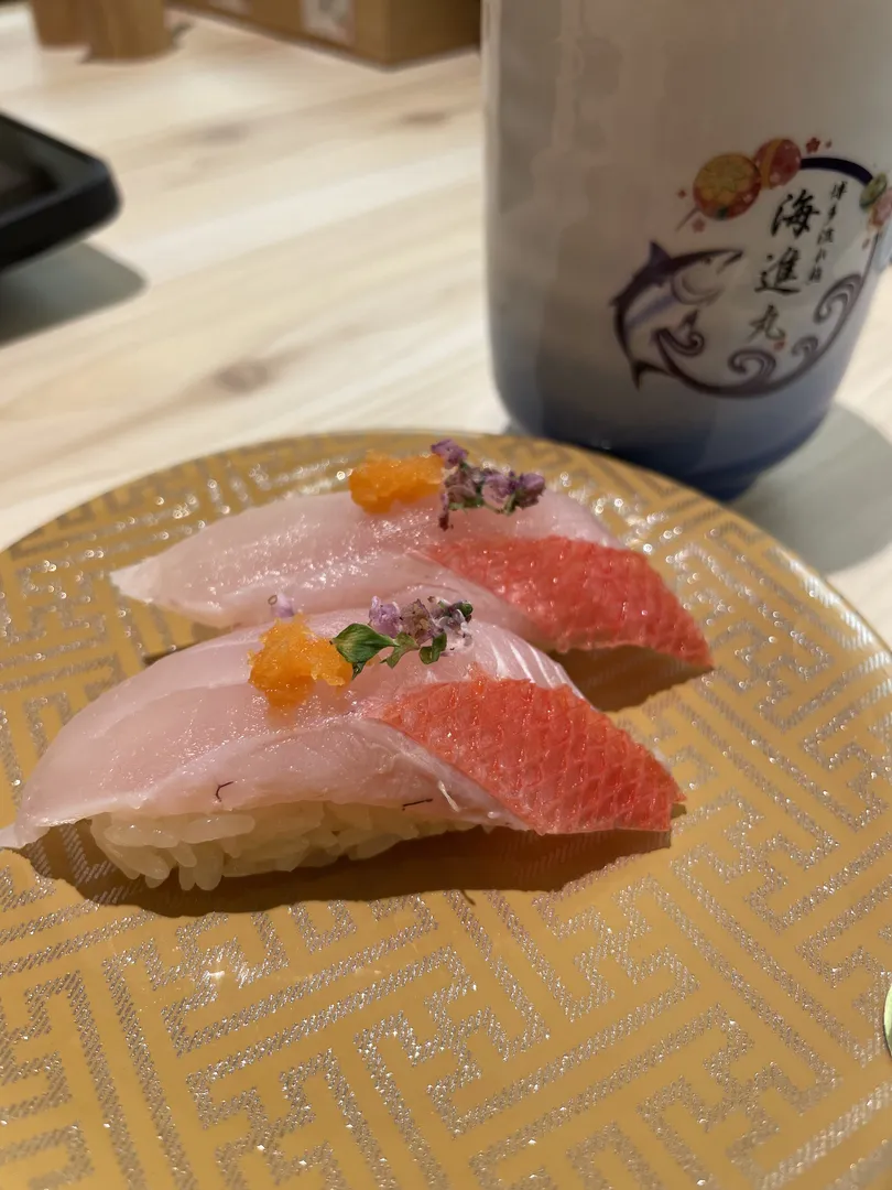 Pair of red-skin alfonsino (kinmedai) nigiri sushi at Kaishinmaru, garnished with chive flowers and orange tobiko