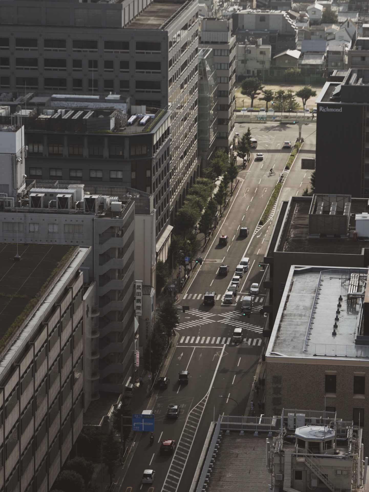 Looking down from Kyoto Tower at the modern downtown street grid with cars at intersections and modern office buildings