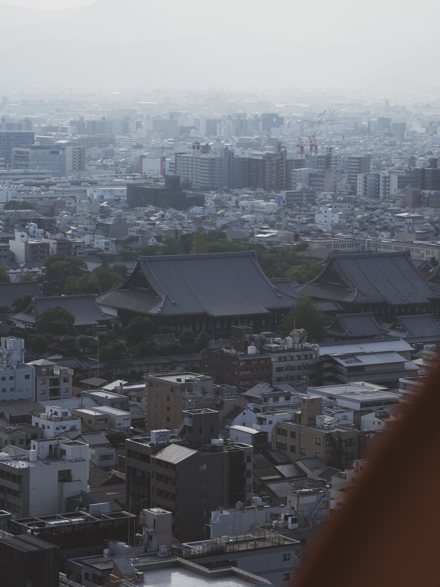 View from Kyoto Tower showing the temple complex of Higashi Hongan-ji with the dense urban grid of Kyoto stretching to the misty hills