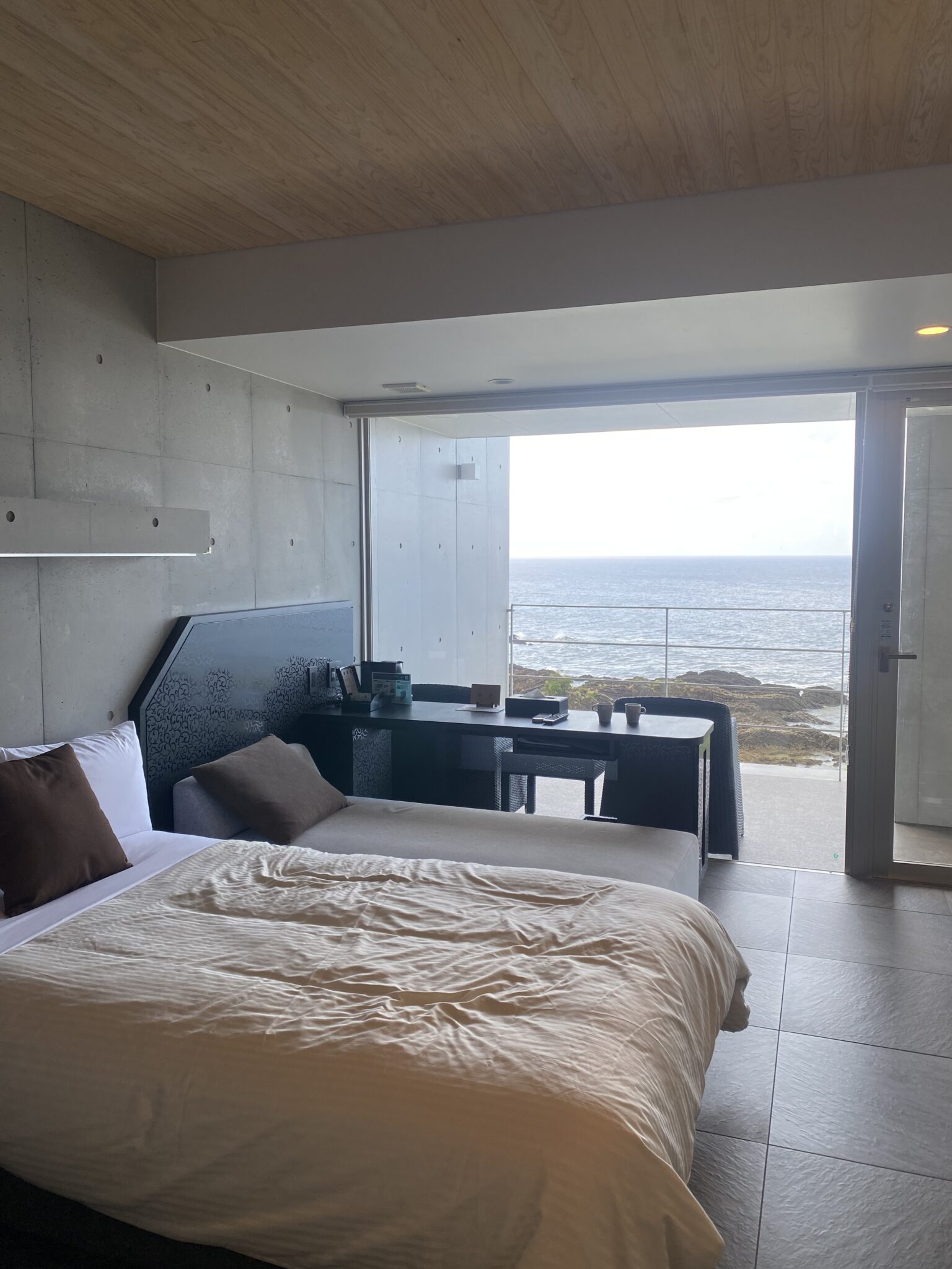 Hotel bedroom with floor-to-ceiling window opening onto the ocean balcony