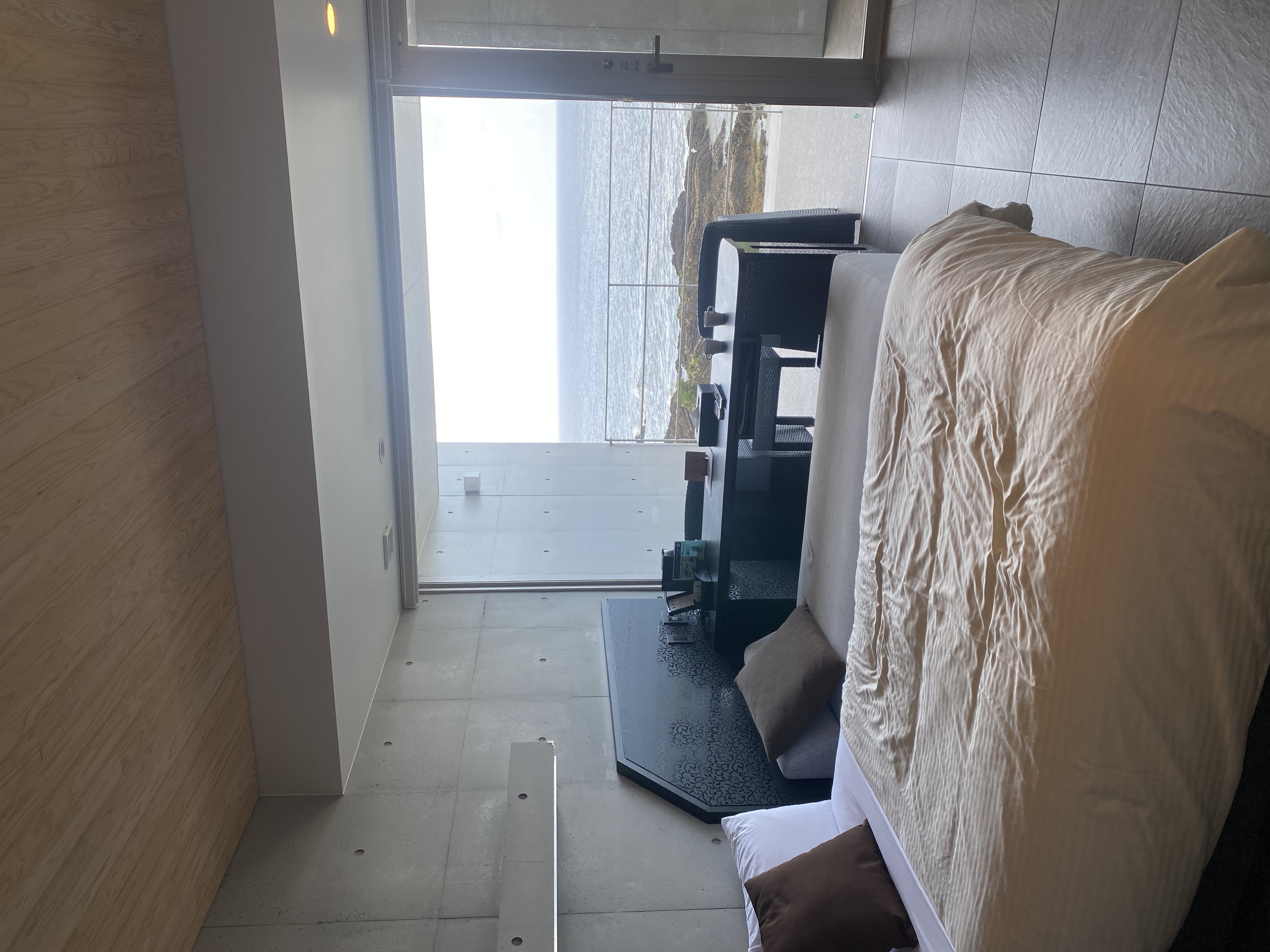 Hotel bedroom with floor-to-ceiling window opening onto the ocean balcony