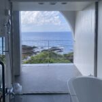 Freestanding bathtub at THE HOTEL YAKUSHIMA with a full-height arch window opening to the Pacific