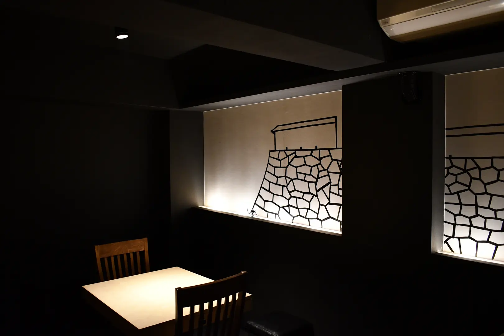 TOAHIS dining table with chairs in front of a backlit washi mural of Fukuoka Castle stone wall and gatehouse