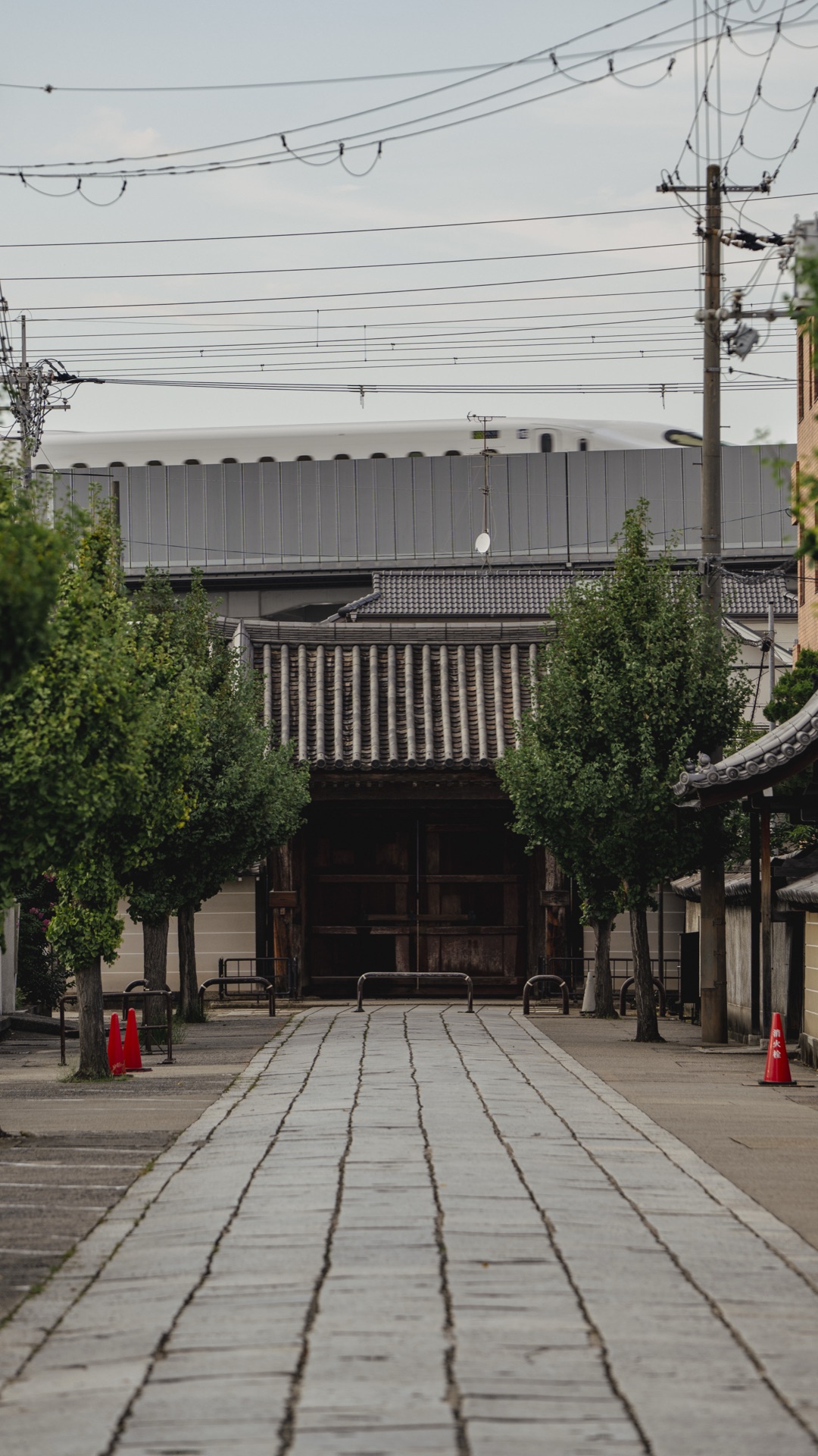 The temple approach path with the white Shinkansen passing on the elevated rail line in the background