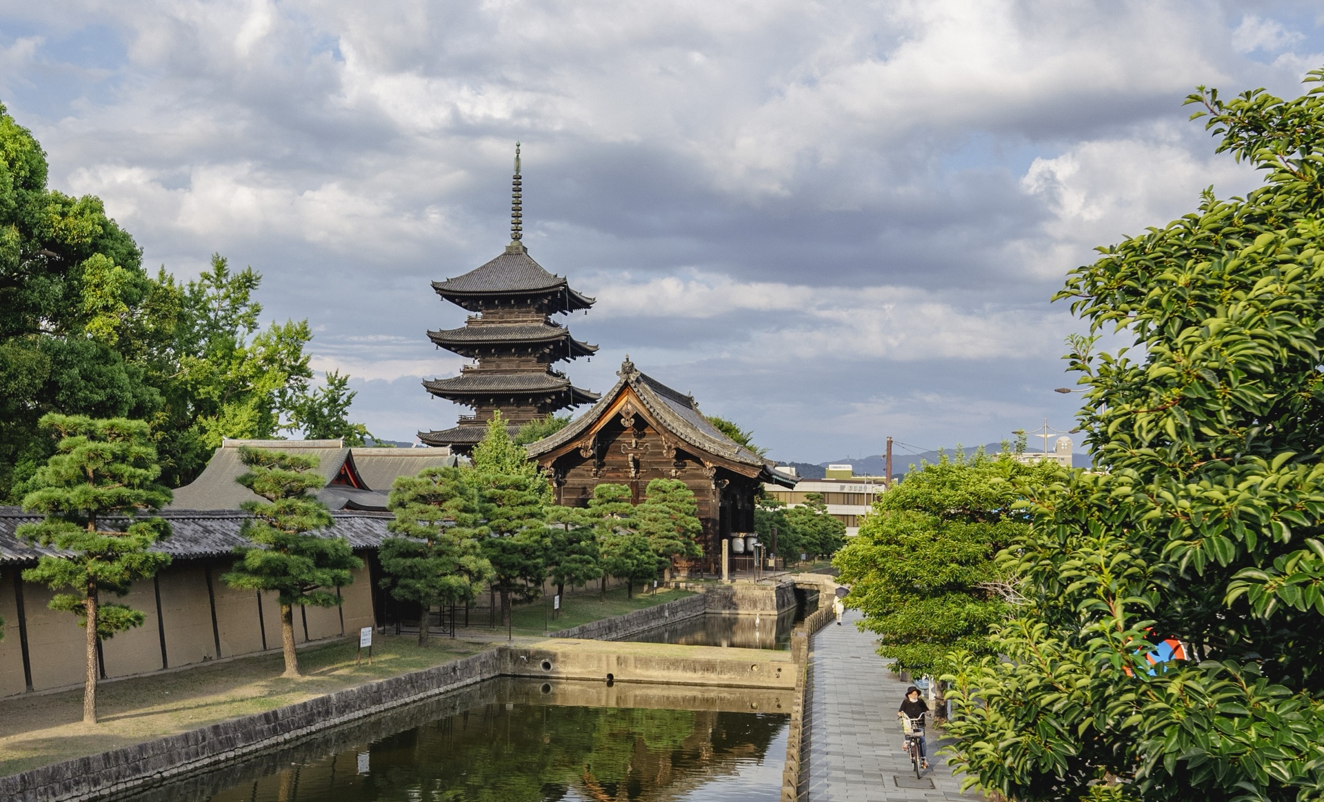 The classic view of Toji five-story pagoda from across the temple canal with a cyclist passing on the path