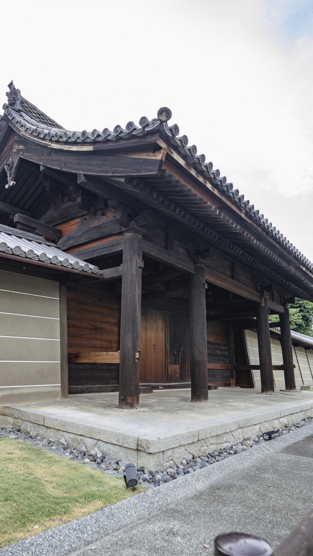 A close view of the wooden side gate architecture at Toji showing the deep eaves the structural beams and the kawara tile roof