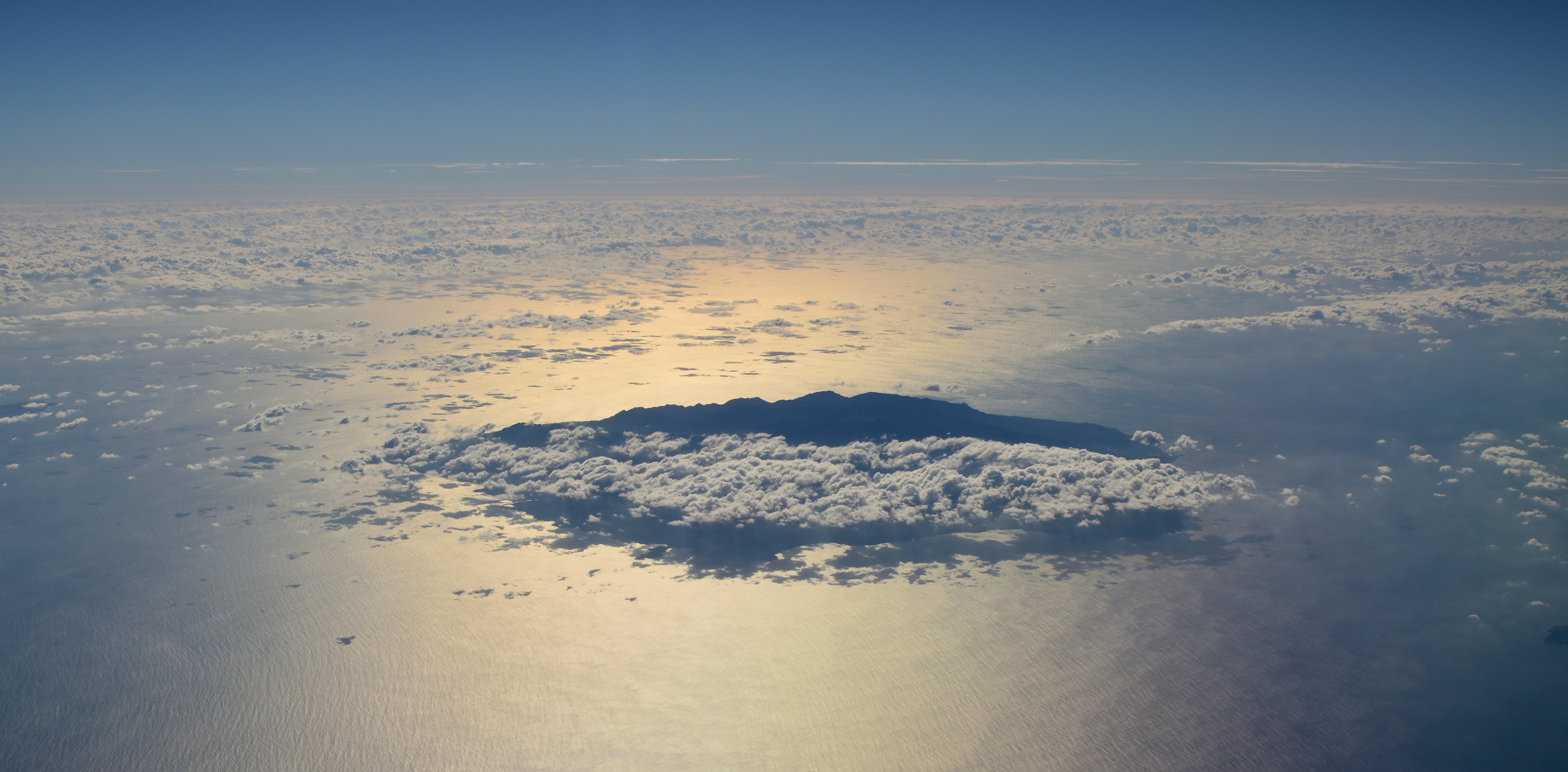 Aerial view of a southern Kyushu island silhouette through clouds at sunrise